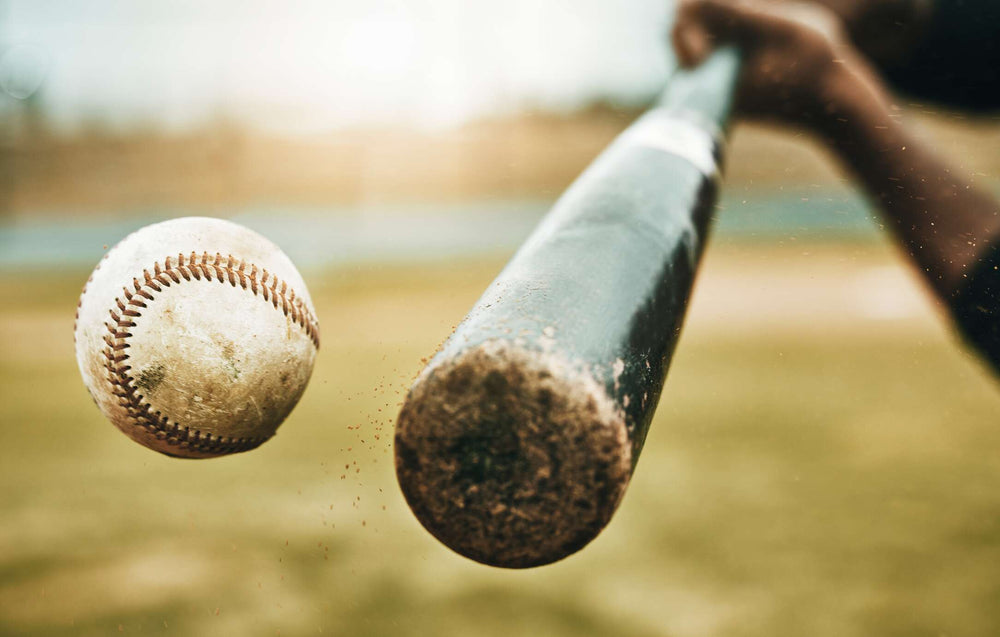 Close-up of a baseball bat hitting an incoming baseball.