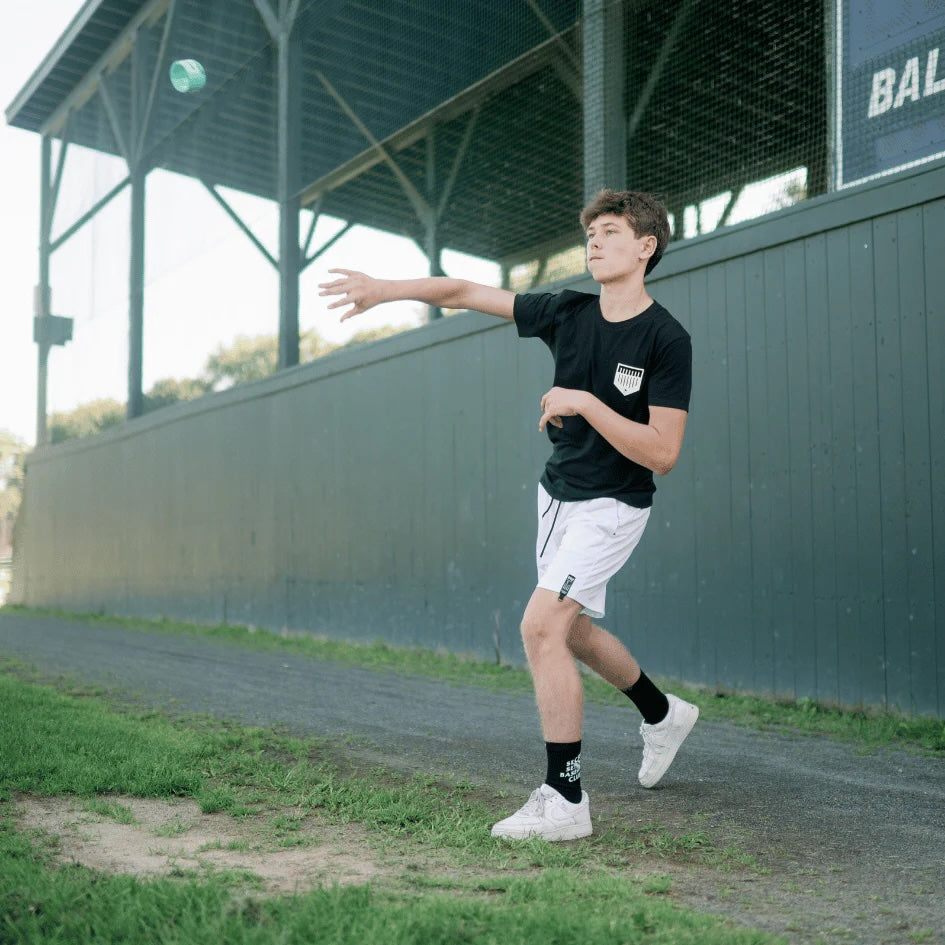 A young baseball player wearing a black Plate Crate shirt throws a Throw Trainer.